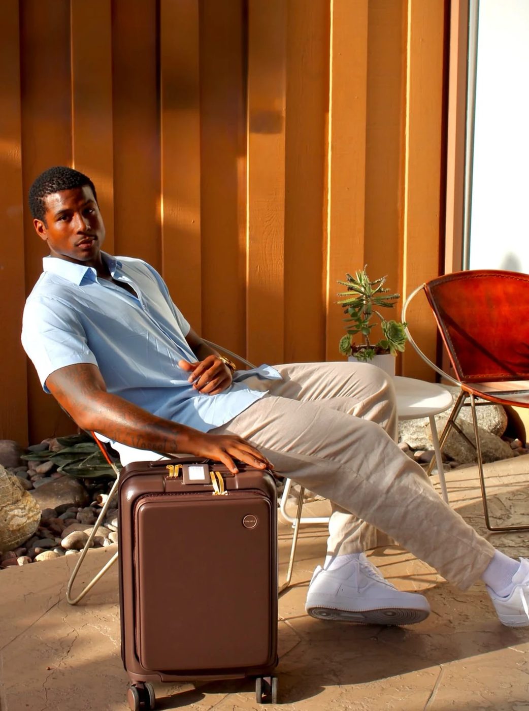 Model on a sunlit patio with a Champs carry-on