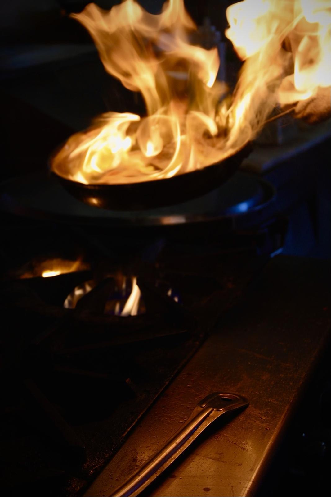Flames rising off a pan in the kitchen at MIYO's