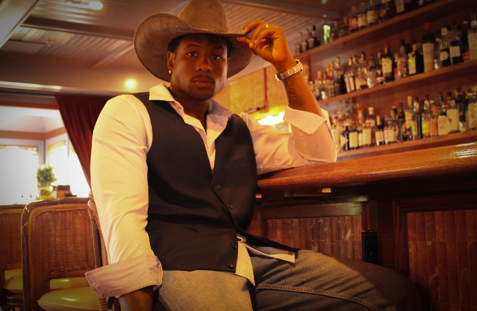 Model in a cowboy hat and vest leaning on the bar at The Chloe