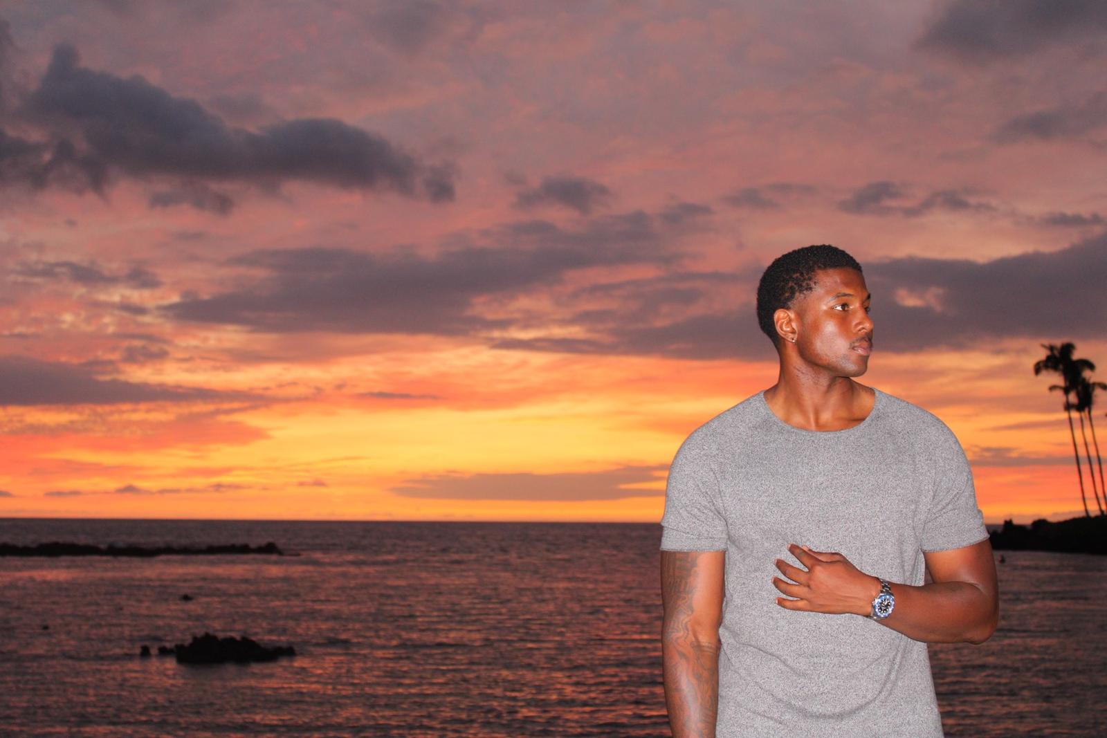 Model in a gray tee at sunset over the ocean